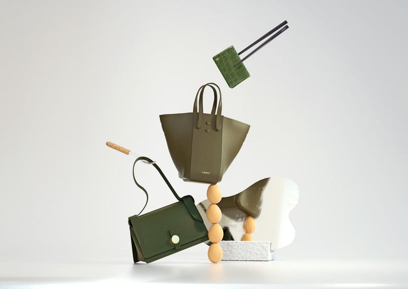 3D animation of three X NIHILO luxury leather khaki goods. Croc cardholder, shoulder bag and hybrid tote bucket bag balancing on 4 eggs.