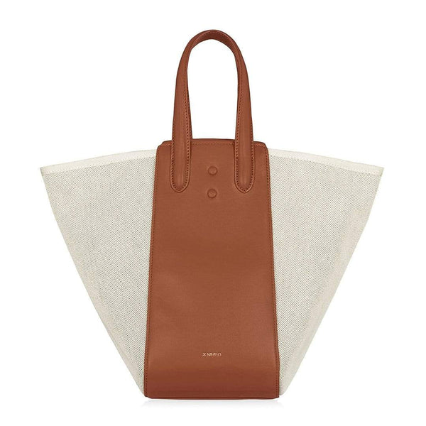 Large tan leather and natural canvas fabric hybrid tote bucket bag, genuine nappa leather bag with handle and logo X NIIHILO embossed in gold on the bottom front.