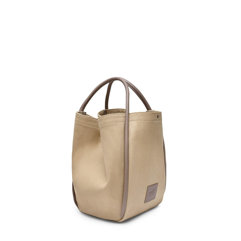 Side view of Camel canvas tote bucket bag, with camel leather rolled leather handles, silver button closure at the top and small square logo of WEST14TH and X NIHILO. Shown as bucket bag, with button used to bring in wings.