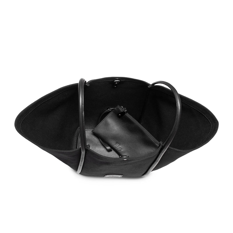 Top inside view of black canvas tote bucket bag, with black leather rolled leather handles, silver button closure at the top and small square logo of WEST14TH and X NIHILO on the bottom front. Shown with included small black leather pouch on the inside.