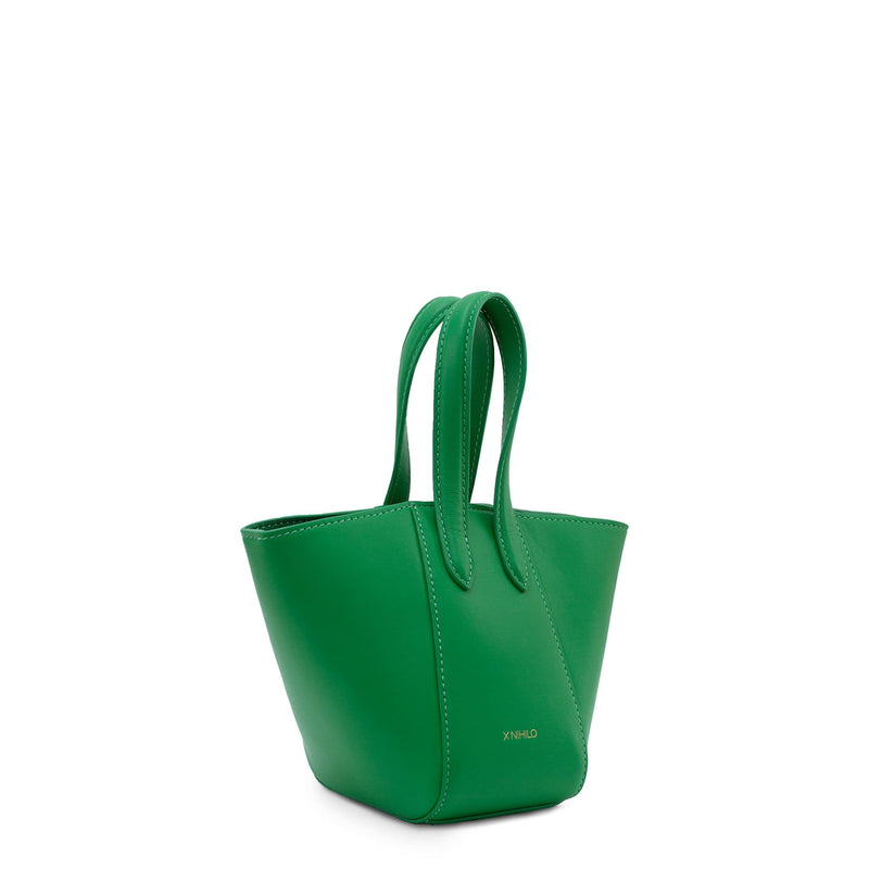 Angled side view of micro bright green leather bucket hybrid handbag, with top handle and X NIHILO embossed in gold on the bottom front.