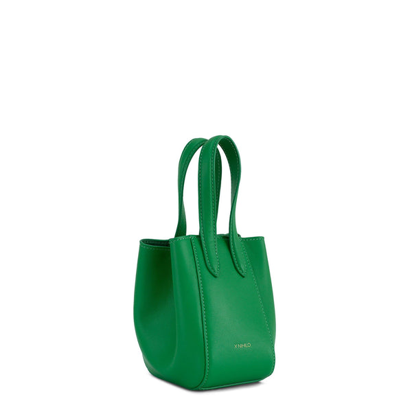 Side angle of Micro bright green leather bucket hybrid handbag, with top handle and X NIHILO embossed in gold on the bottom front.