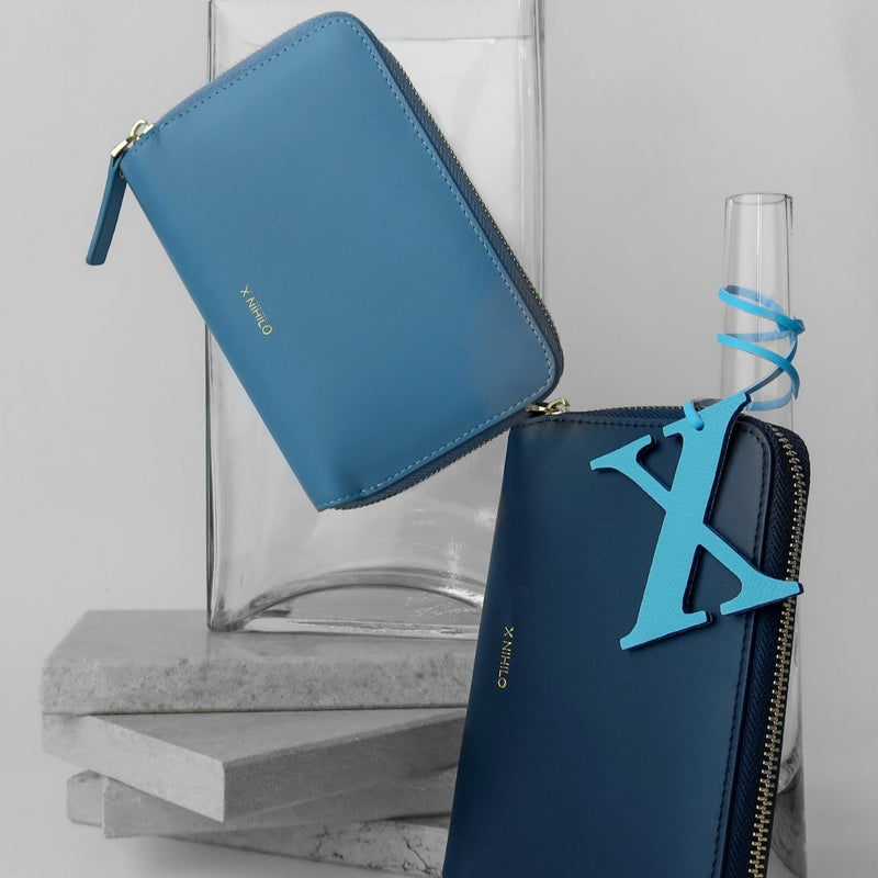 X NIHILO 'X' bag charm, light blue, textured calf leather, pictured with blue X NIHILO Cameron passport wallets