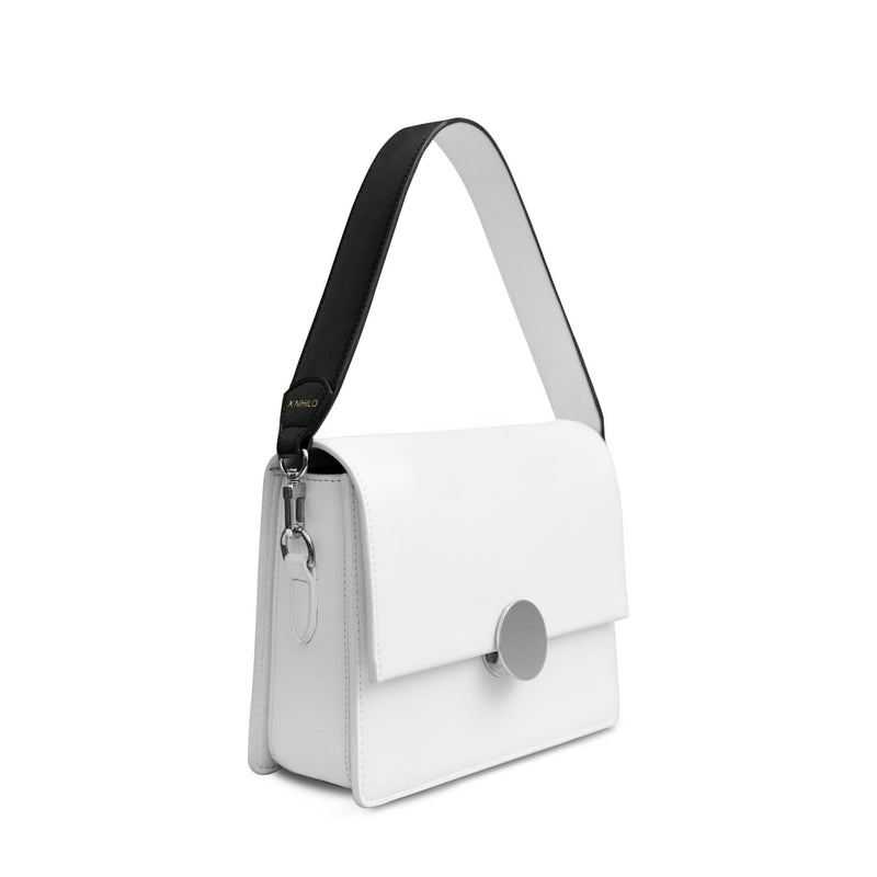 white luxury leather bag, with genuine nappa leather black and white bag strap with silver hardware and X NIHILO logo embossed in gold near clasp.