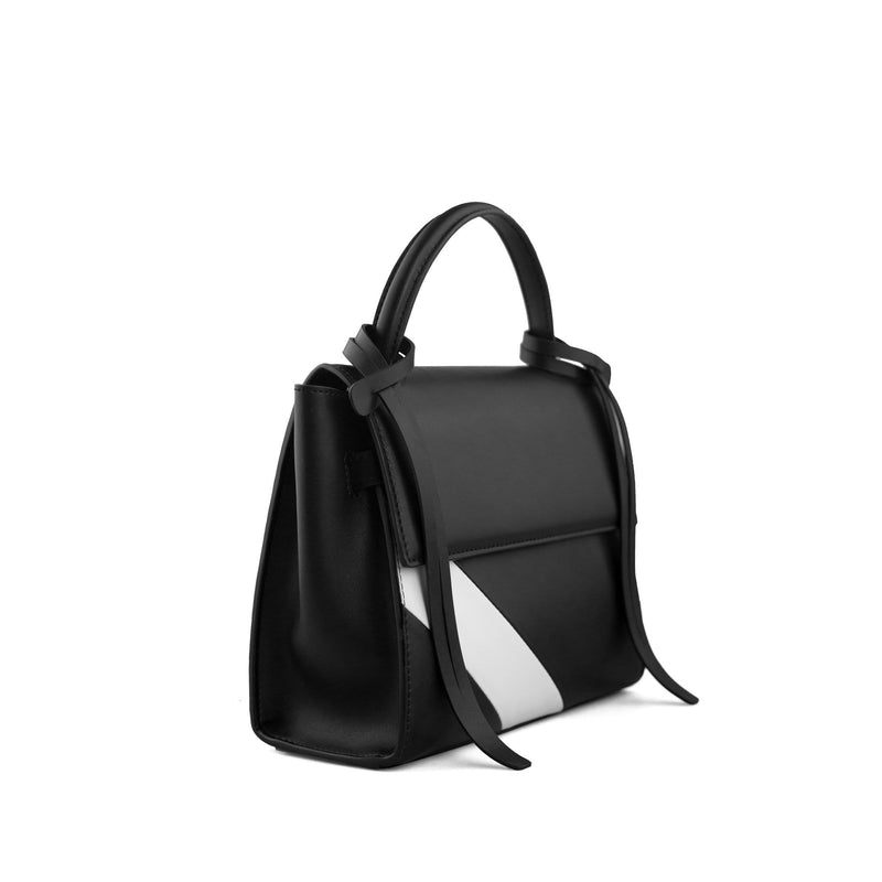Angled side view of rectangle genuine black and white cow nappa leather work bag and handbag with black leather tassels, front flap and handle.