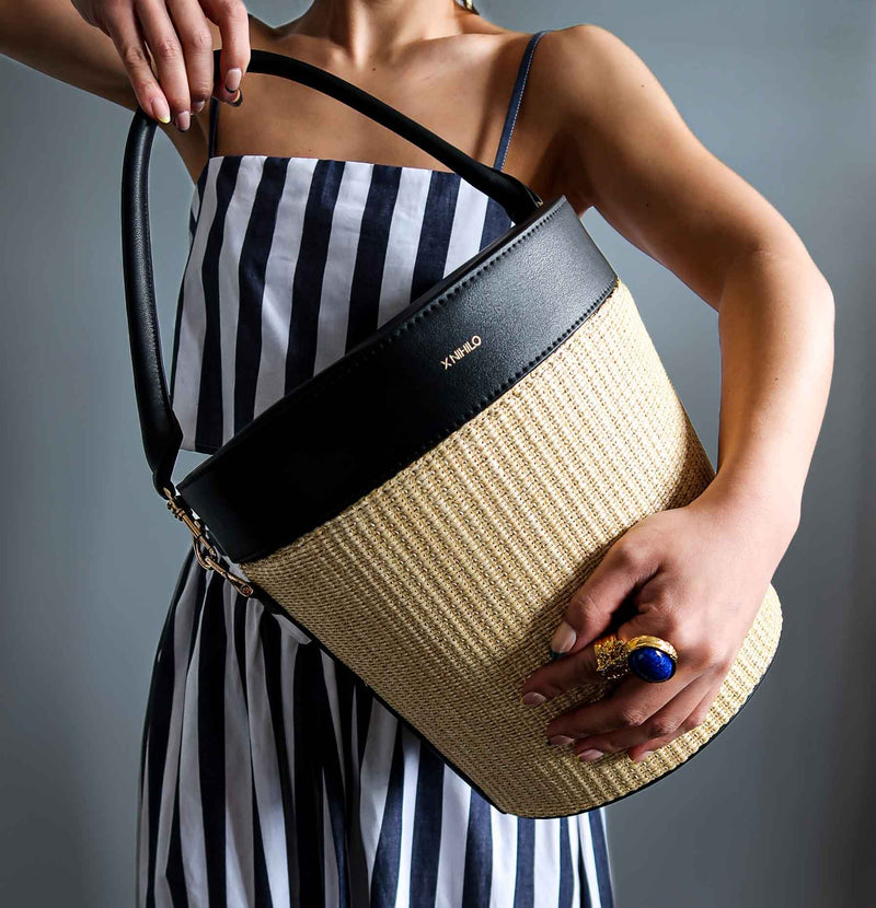 Model carrying the raffia picnic basket with black leather top on the side and detachable leather handle.