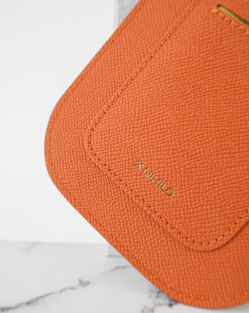 Rectangular Tangerine orange phone pouch with opening on top and an attached shoulder strap. Back view of the logo