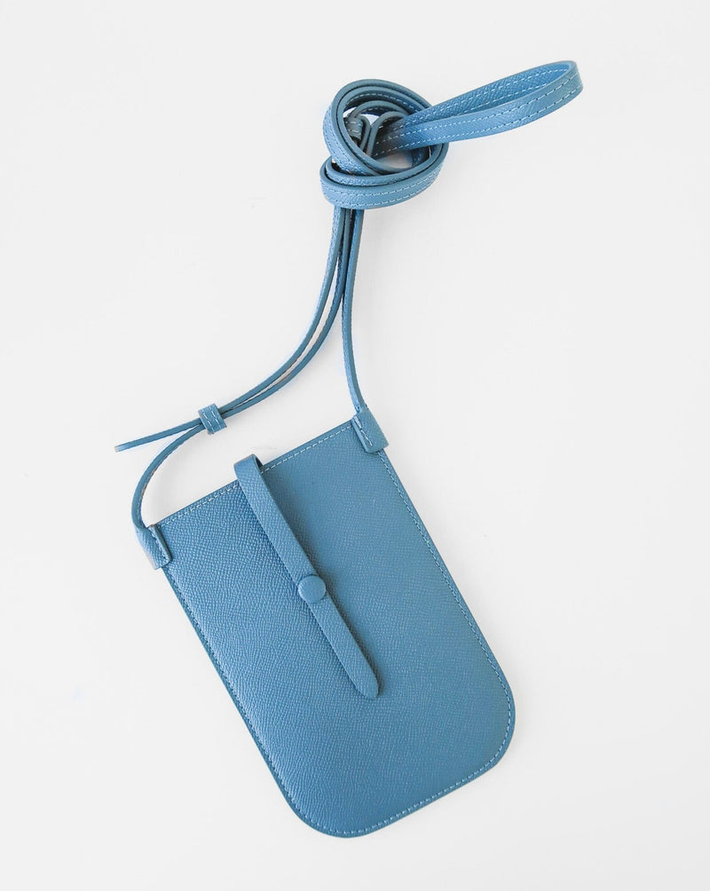 Rectangular Chambray blue phone pouch with opening on top and a attached shoulder strap against white background