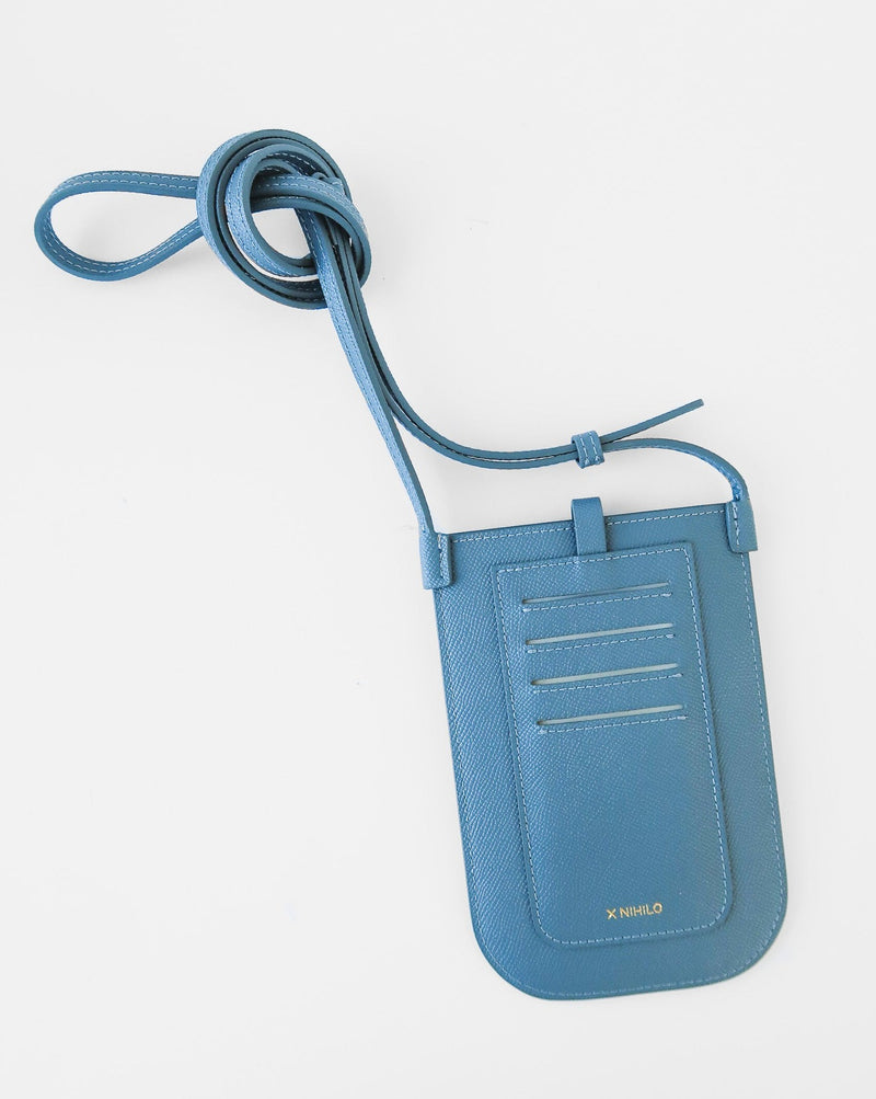 Rectangular Chambray blue phone pouch with opening on top and a attached shoulder strap against white background. Back view