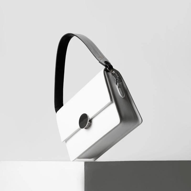 white luxury leather bag, with genuine nappa leather black and white bag strap with silver hardware and X NIHILO logo embossed in gold near clasp.