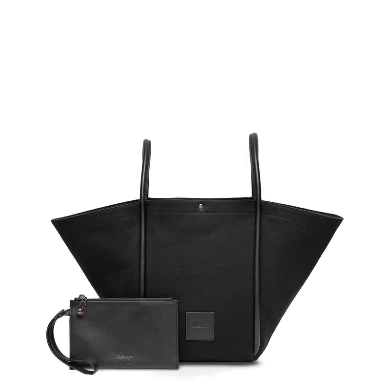 Black canvas tote bucket bag, with black rolled leather handles, silver button closure at the top and small square logo of WEST14TH and X NIHILO. Small black leather pouch shown in front with hand strap.