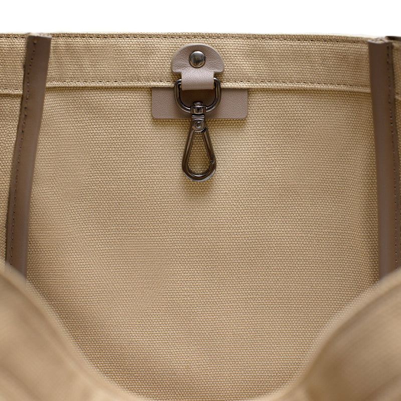 Inside view of Camel canvas tote bucket bag, with leather detailing and silver internal clip shown.