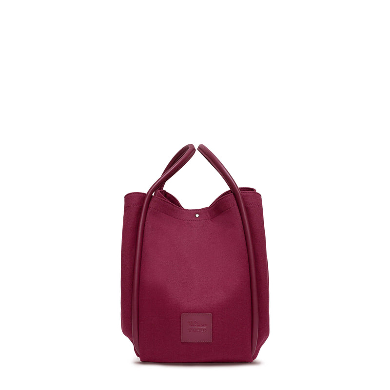 Burgundy canvas tote bucket bag, with burgundy leather rolled leather handles, silver button closure at the top and small square logo of WEST14TH and X NIHILO. Shown as bucket bag, with button used to bring in wings.