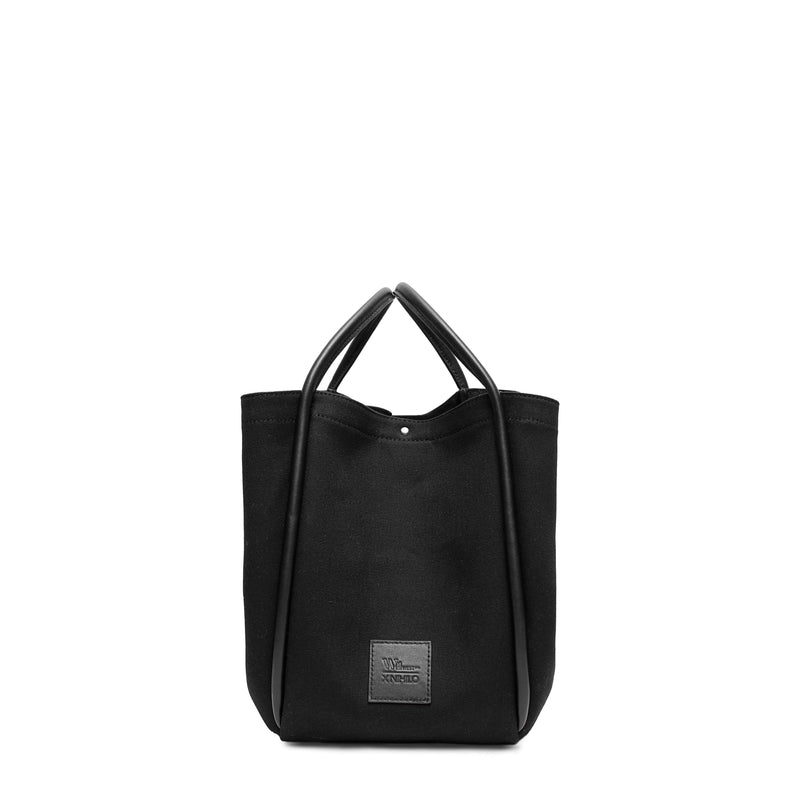 Black canvas tote bucket bag, with black leather rolled leather handles, silver button closure at the top and small square logo of WEST14TH and X NIHILO. Shown as bucket bag, with button used to bring in wings.