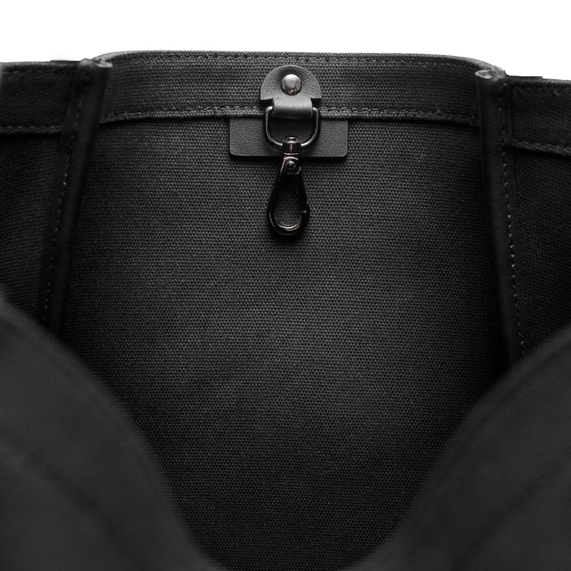Inside view of Black canvas tote bucket bag, with leather detailing and silver internal clip shown.