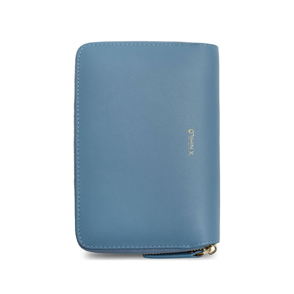 Sky blue genuine cow nappa leather wallet and passport holder placed vertically with X NIHILO logo embossed in gold on the side.