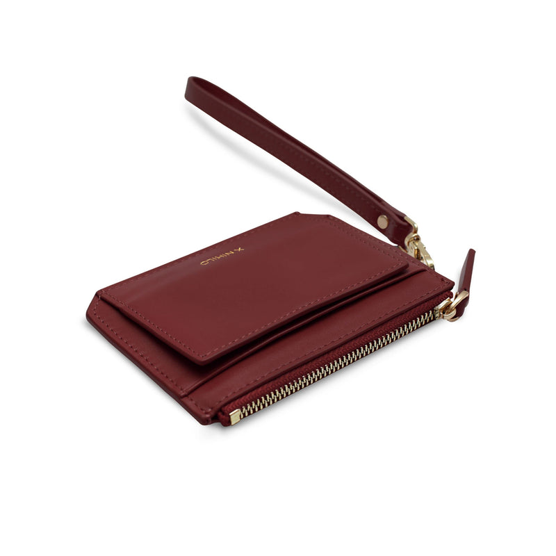 Angled view of small red genuine cow nappa leather coin purse and wallet with detachable leather strap, placed on its back.
