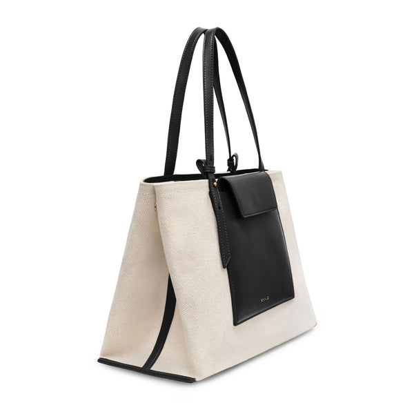 Angled side view of black leather and natural canvas fabric fashion tote bag with black leather handle.