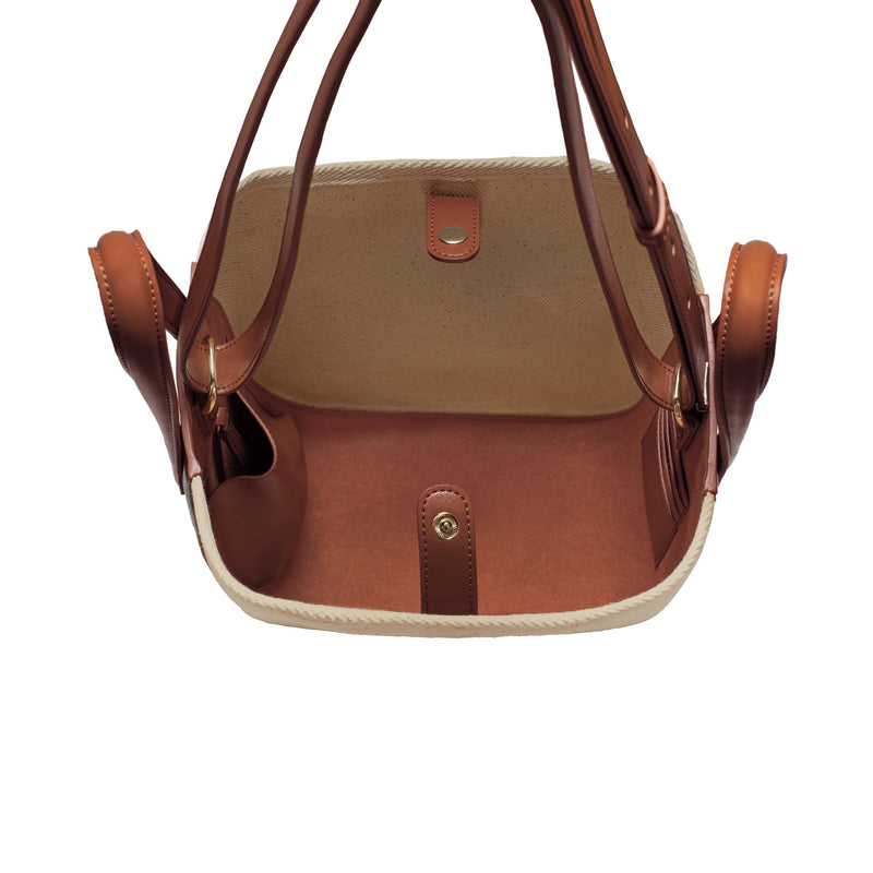 Top view of tan leather and natural canvas tote bucket bag, genuine nappa leather bag with handle and logo X NIIHILO embossed in gold on the bottom front.